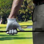 male golfer on a golf course holding a six iron behind his body