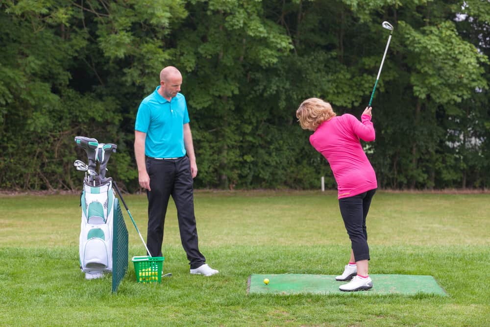 A lady golfer being taught to play golf