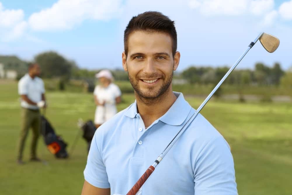 Closeup portrait of handsome young male golfer with golf club