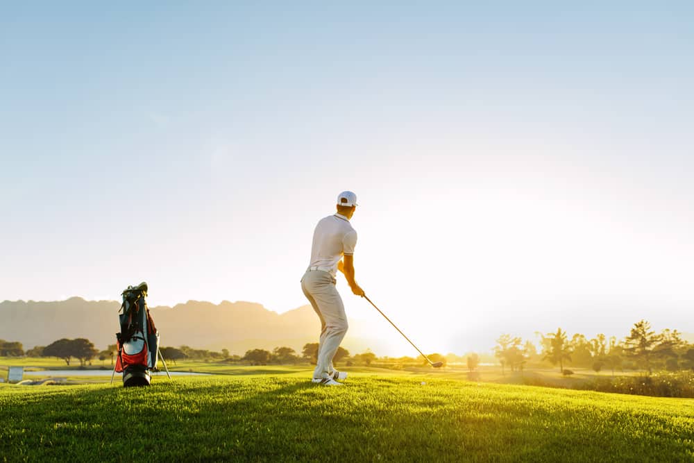 Full length of golf player playing golf on sunny day