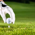 Hand hold golf ball with tee on course