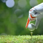 Hand hold golf ball with tee on golf course