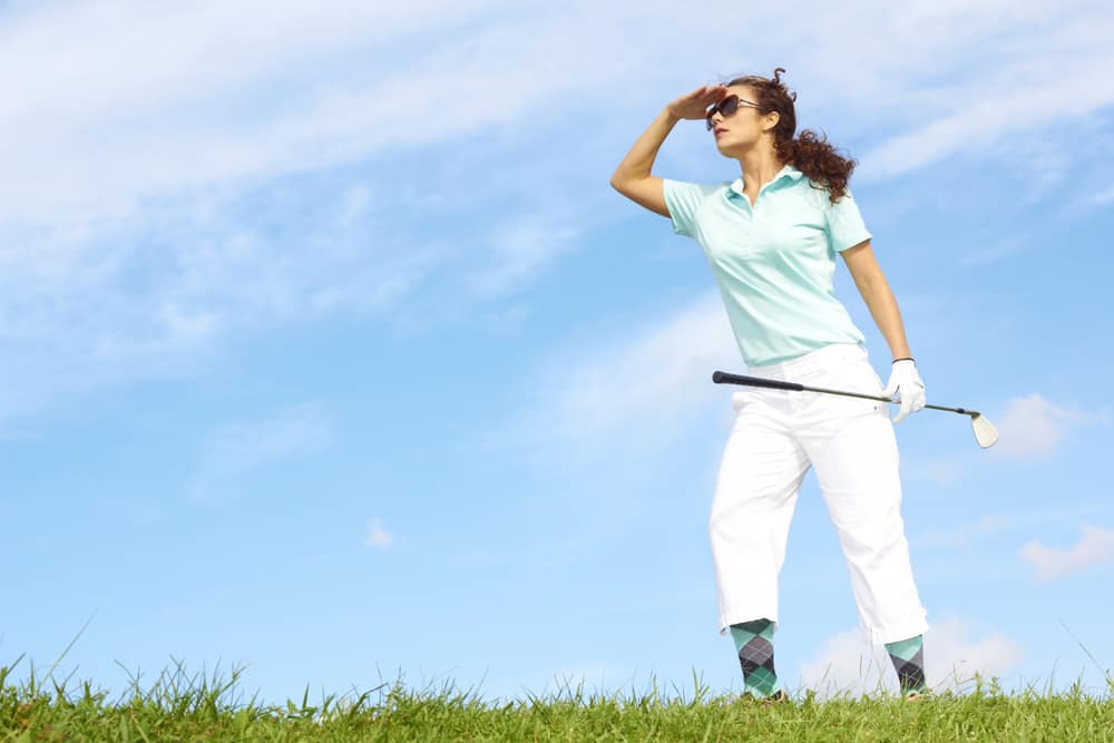 Lost female golfer holding golf club looking for golf ball