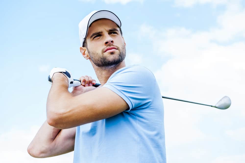 Low angle view of young golfer swinging his driver