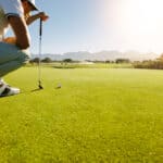 Male golfer on putting green about to take the shot