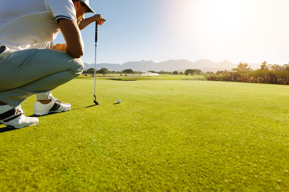 Male golfer on putting green about to take the shot