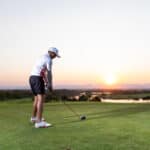 Pro golfer taking a shot at the sunset