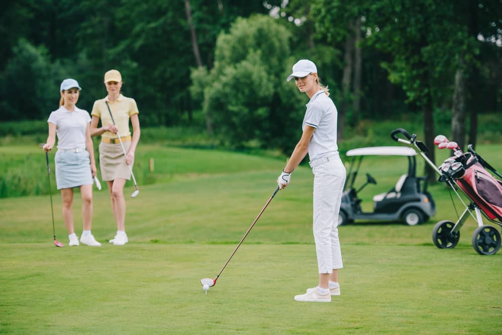 Selective focus of woman in cap playing golf