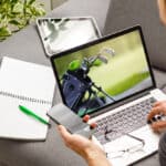 View of lecture app against man holding mobile phone while typing on laptop at desk
