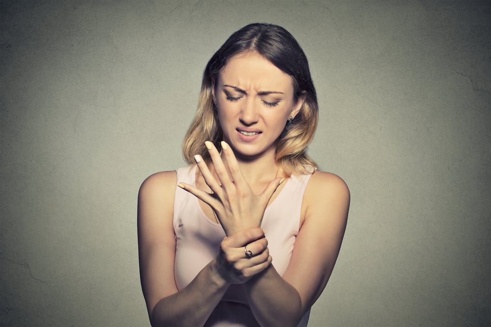 Young woman holding her painful wrist