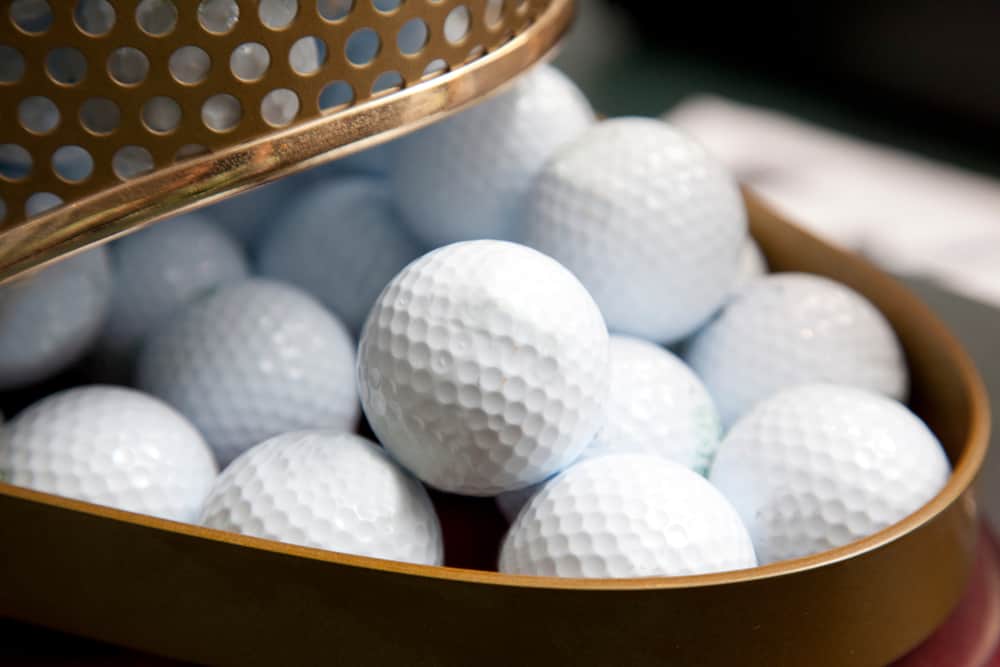 container of white golf balls at a pro shop