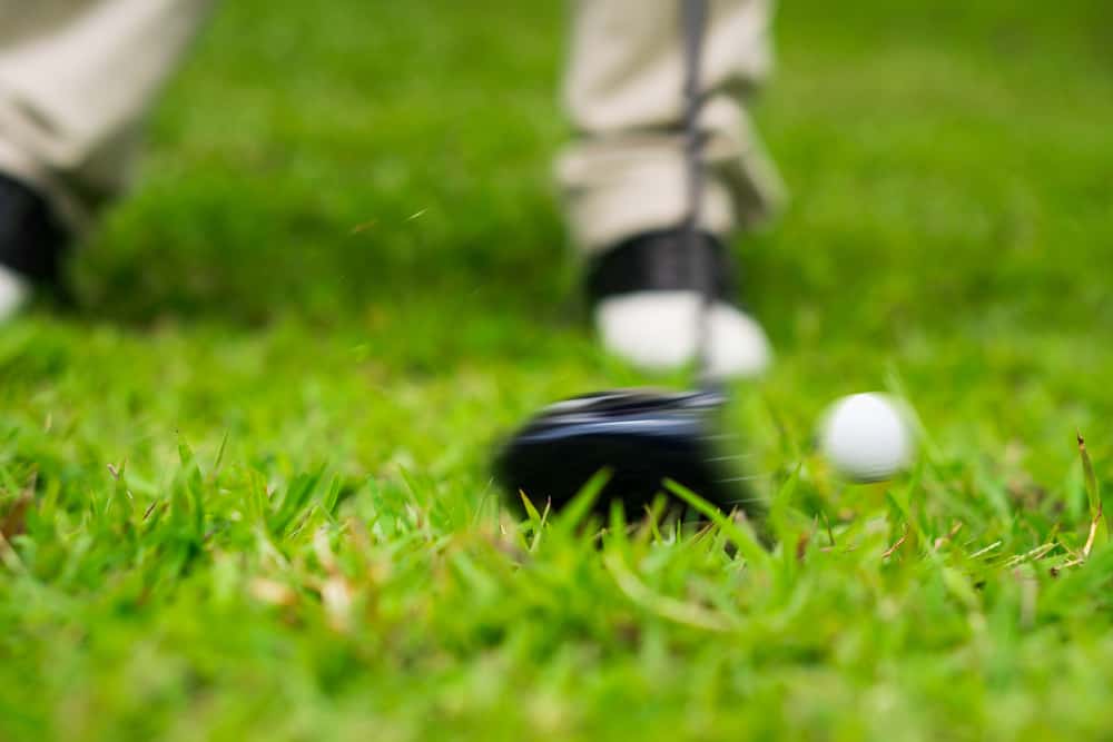 golfer swing hitting golf ball from rough grass