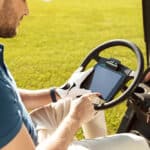 male golfer sitting in a golf cart and using tablet computer