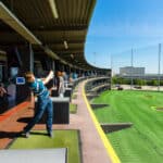 man hits a golf ball at a Top Golf golfing complex