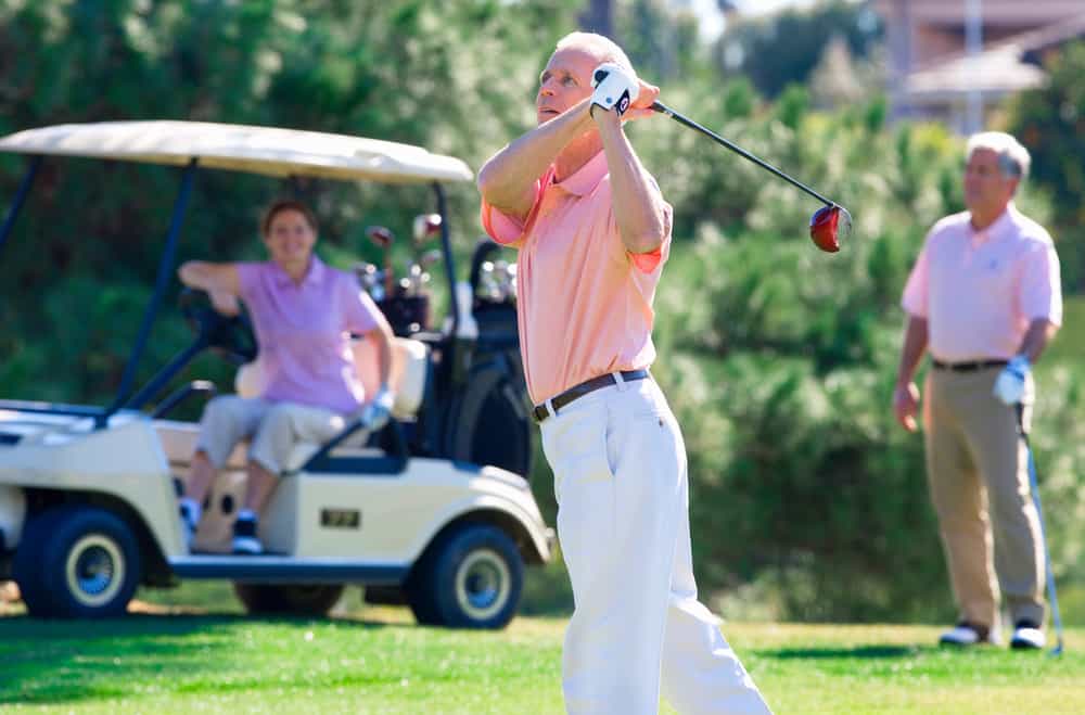 playing golf on course with man driving ball from tee