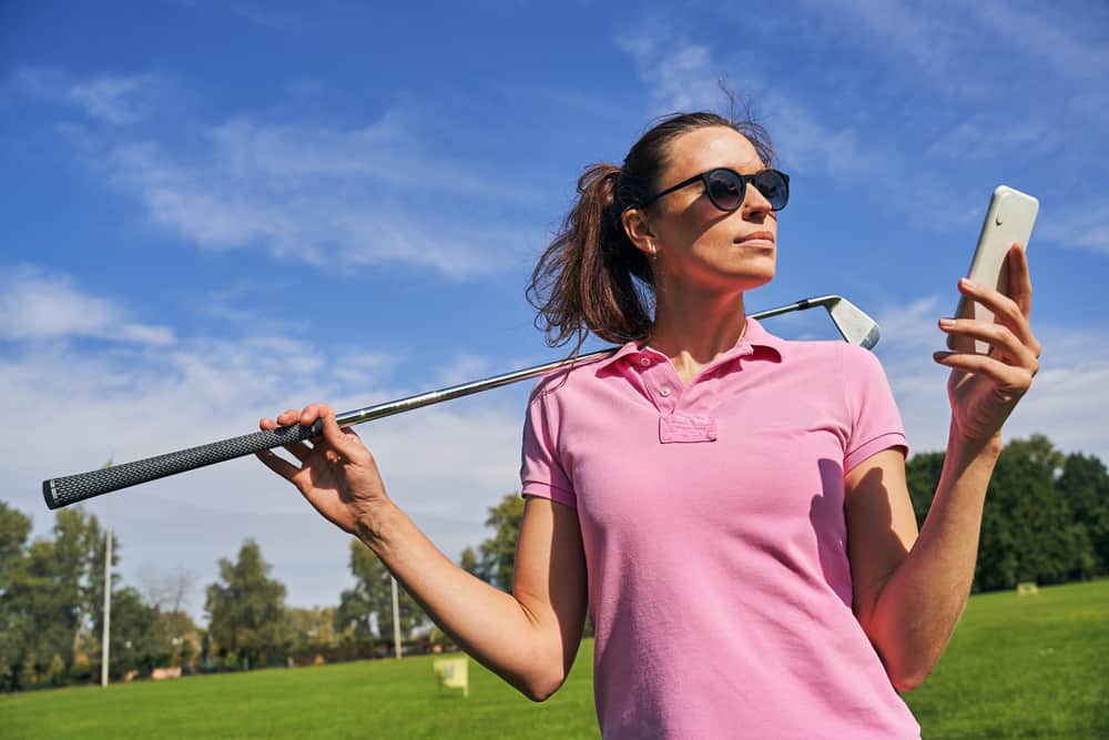 sportswoman with a golf club staring at her mobile phone