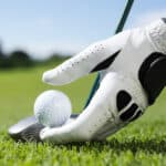 Golfer placing golf ball on tee on a sunny day at the golf course