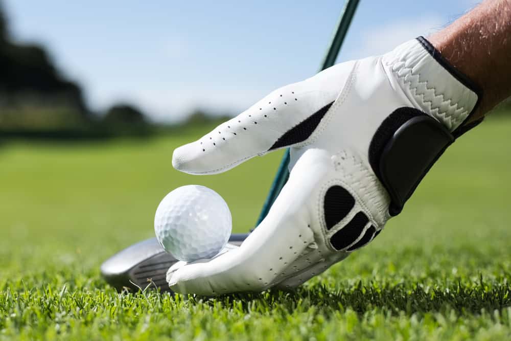 Golfer placing golf ball on tee on a sunny day at the golf course