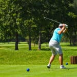 Young Man on Golf Course Hitting an Iron off the Tee