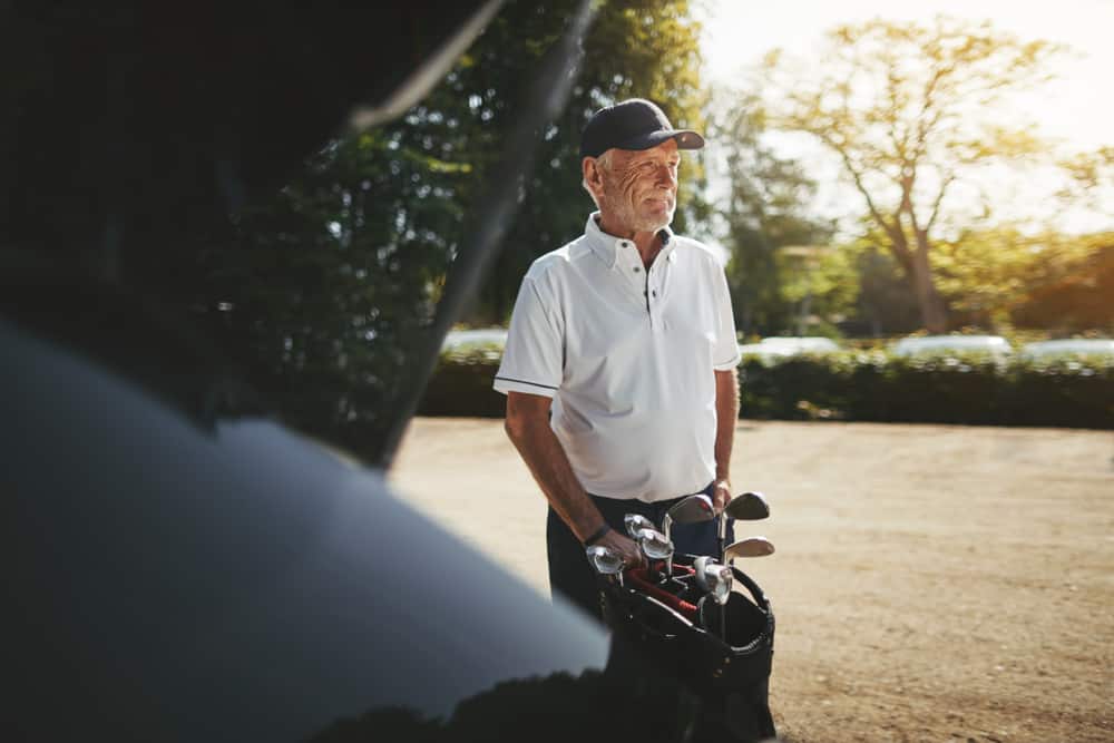 man packing his clubs into the trunk of his car