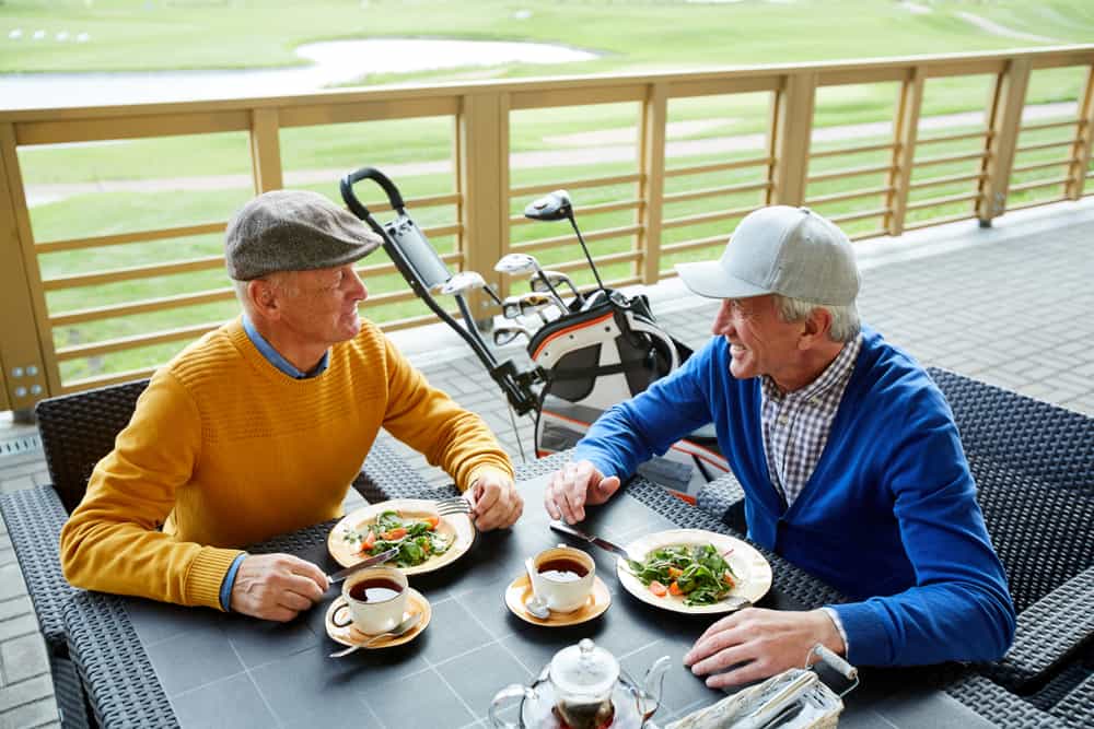 men sitting in outdoor cafe, having lunch and discussing curious moments of the last game of golf