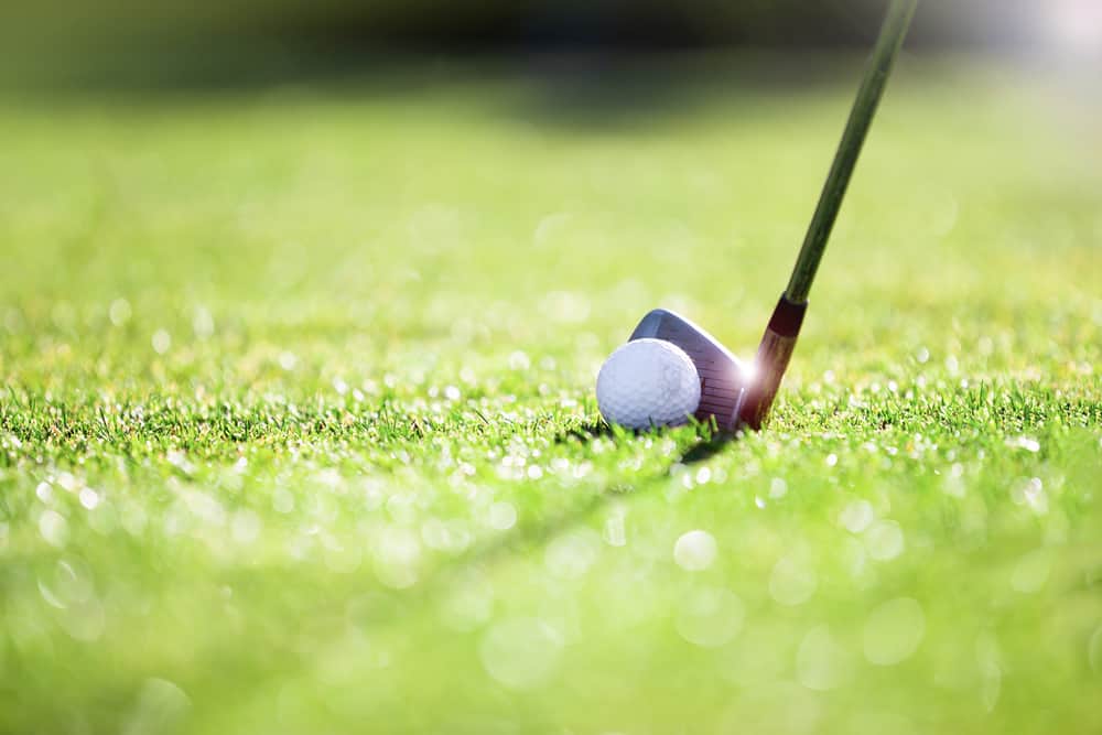 Golfer hitting iron club on golf course on fairway