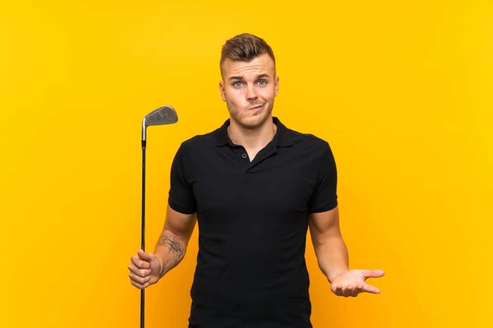 Golfer player man over isolated yellow background making doubts gesture while lifting the shoulders