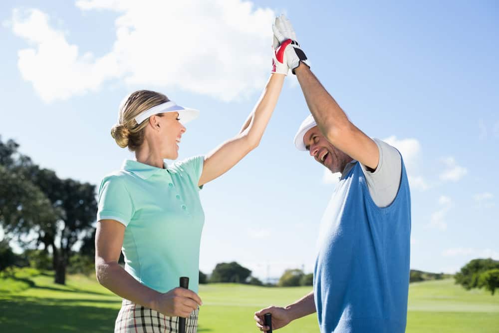 Golfing couple high fiving on the golf course on a sunny day at the golf course