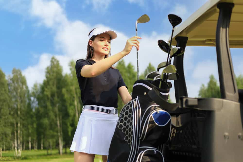 Professional woman golf player choosing the golf club