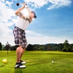 Young golf player on course doing golf swing
