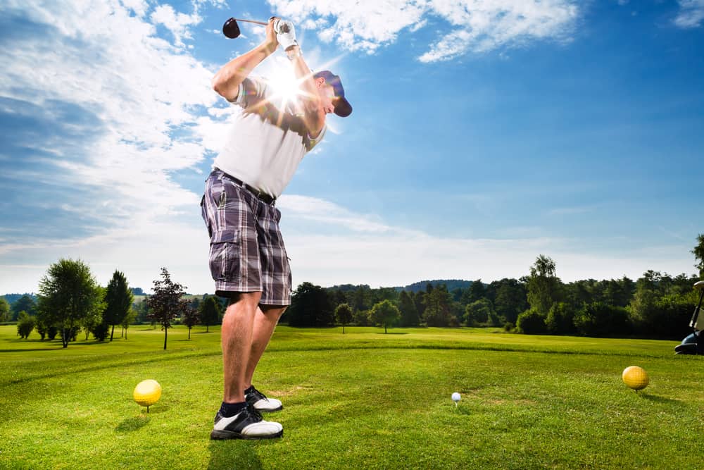 Young golf player on course doing golf swing