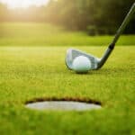 close up golf club and golf ball on green grass