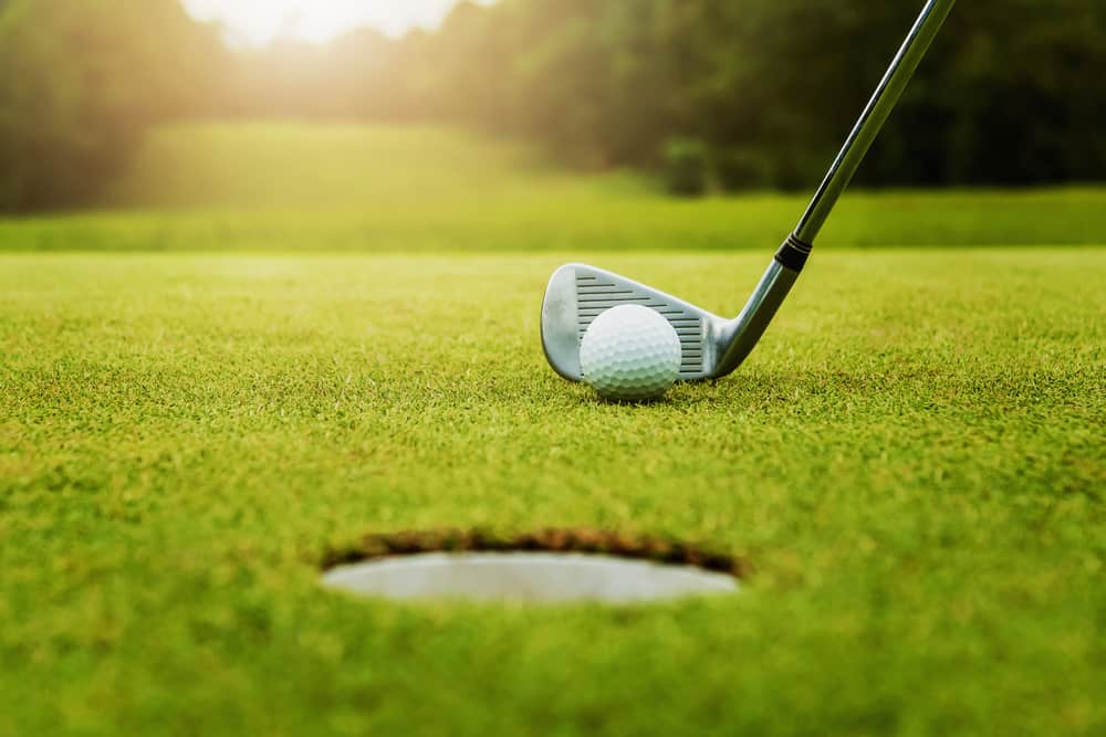 close up golf club and golf ball on green grass