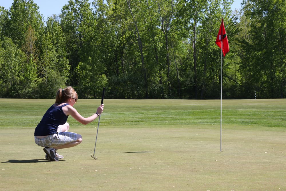 college aged girl surveying her putt on the last hole