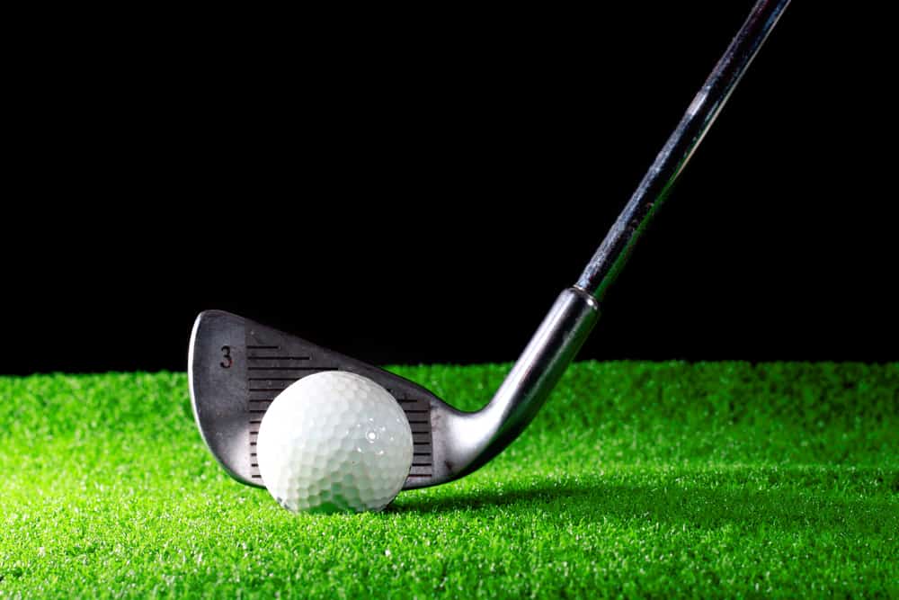 golf iron and golf ball on green grass