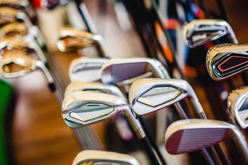 A shiny metal golf clubs for sale show in shop rack.