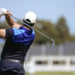 Golfer hits a fairway shot towards the club house