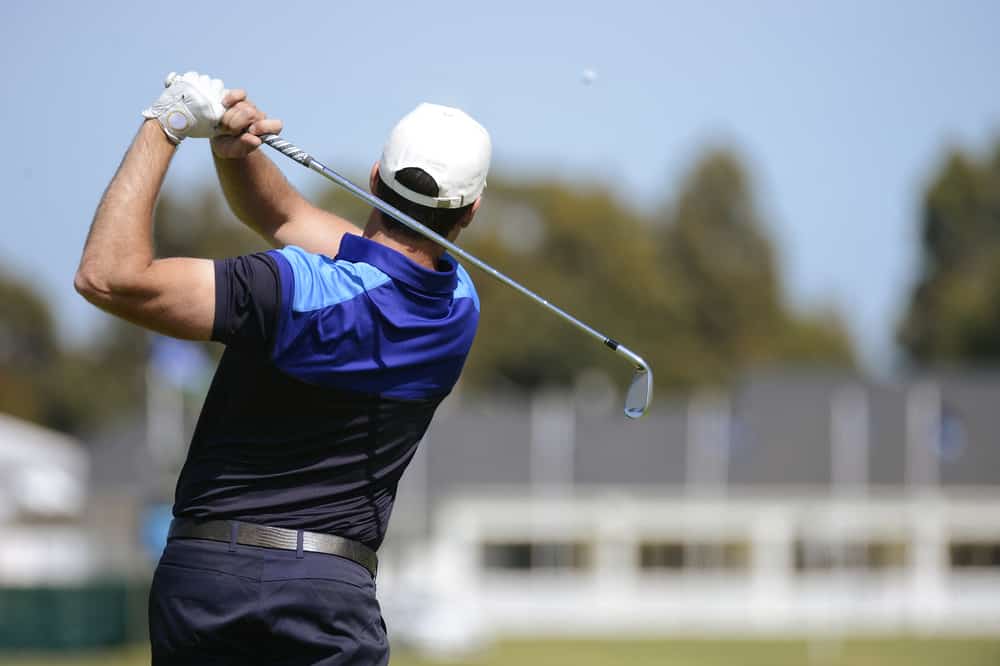 Golfer hits a fairway shot towards the club house