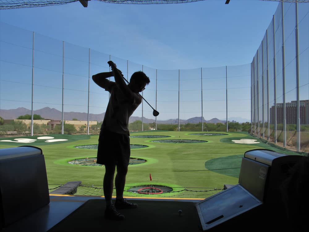 The silhouette of a person playing at the TopGolf driving range