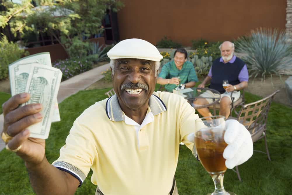 male golfer holding money and drink with people