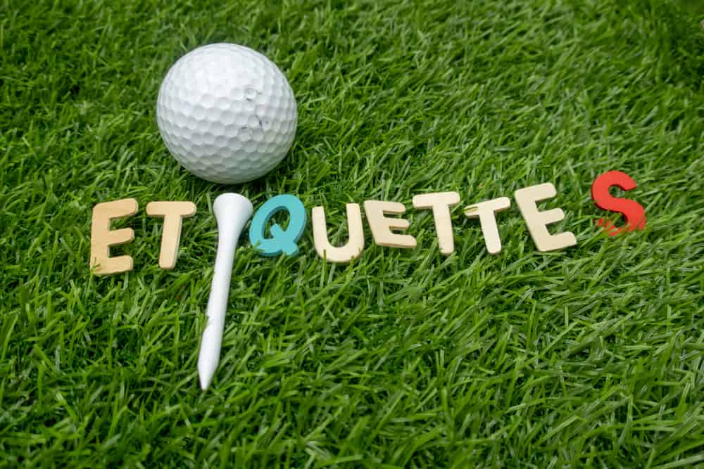 Etiquette word with golf ball and tee is on green grass