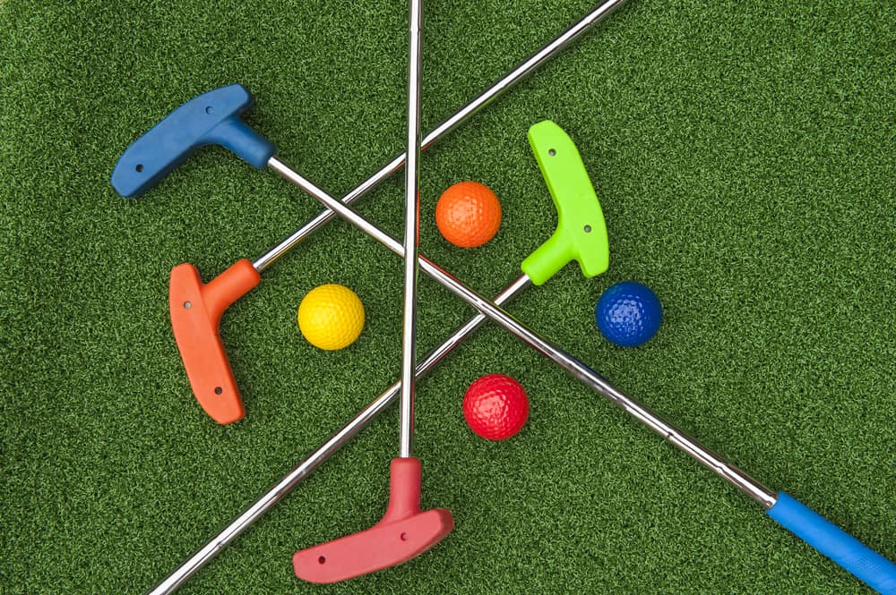 Four mini golf putters and balls of assorted colors