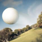 Golf ball flying over green field