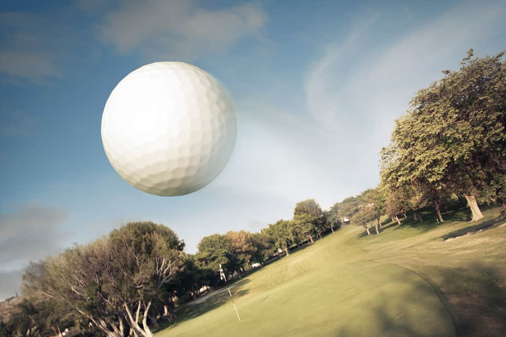 Golf ball flying over green field