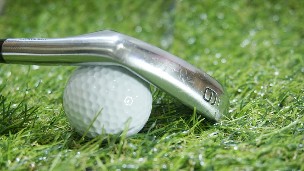 Golf iron and ball on green grass - iron 9