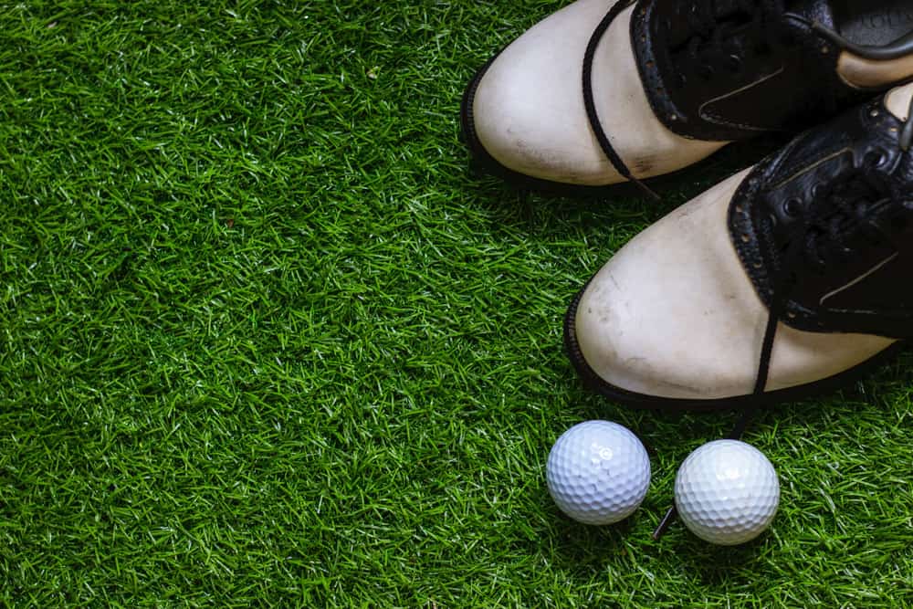 Golf shoes and golf ball on green grass