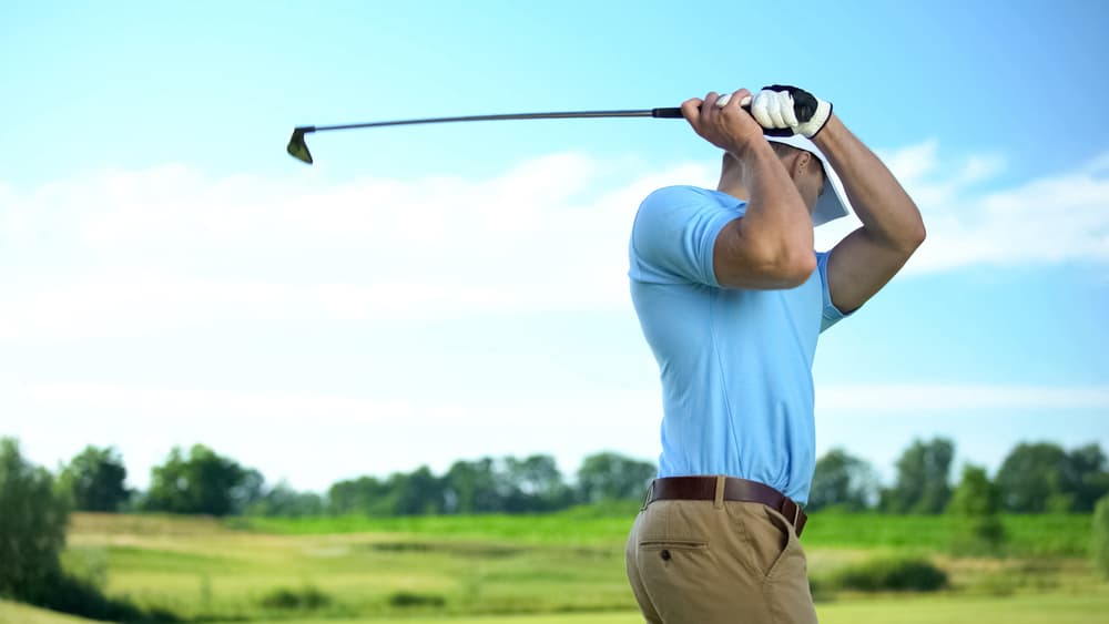 Male golfer hitting ball performing draw position