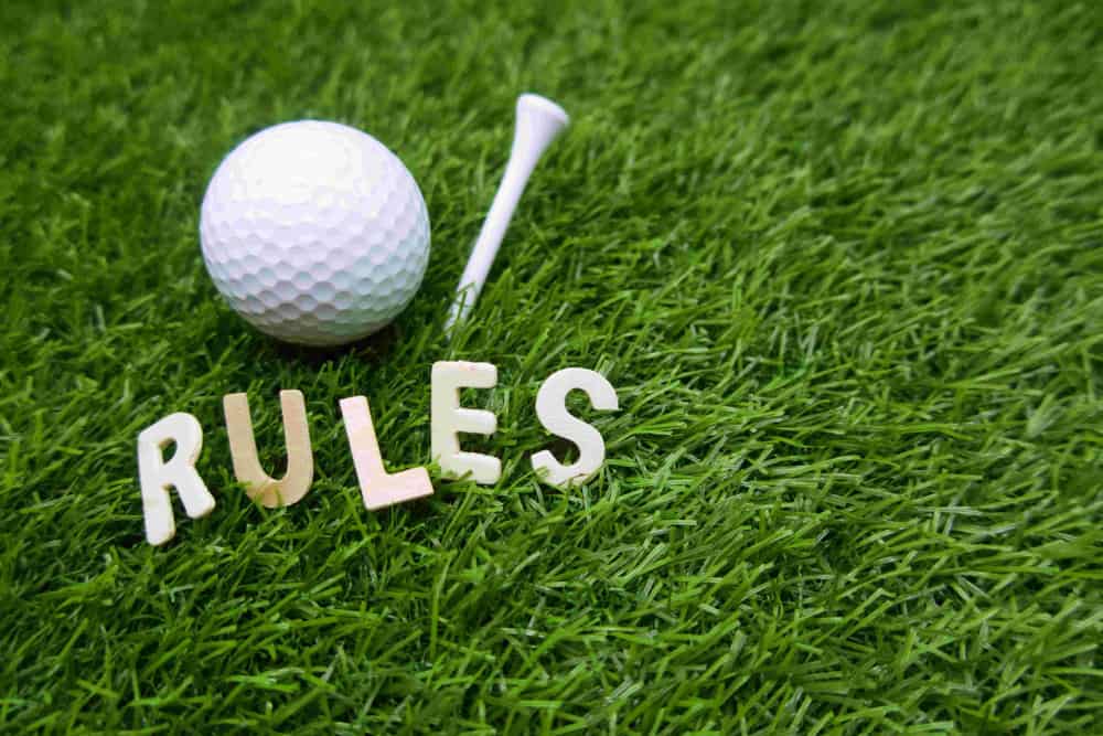 Rules of golf with golf ball and rules word on green grass