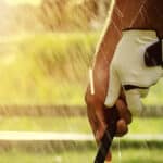 The hands of golfers are holding golf clubs by the wet rain