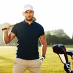male golfer standing with golf club on a green field